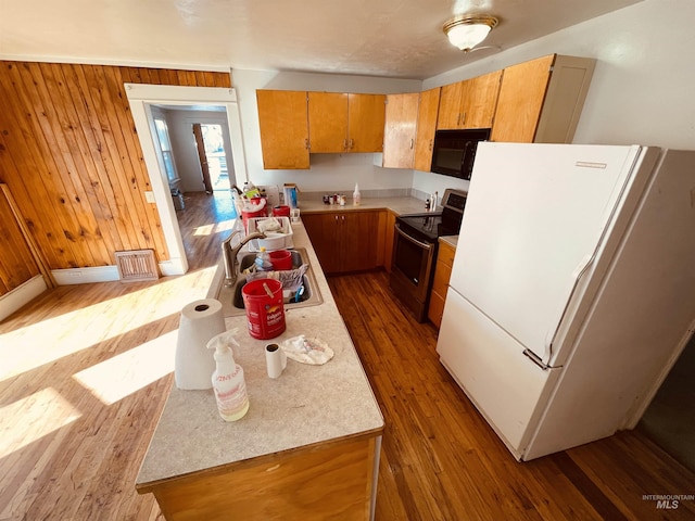 kitchen with dark wood-style flooring, electric range, freestanding refrigerator, a sink, and black microwave