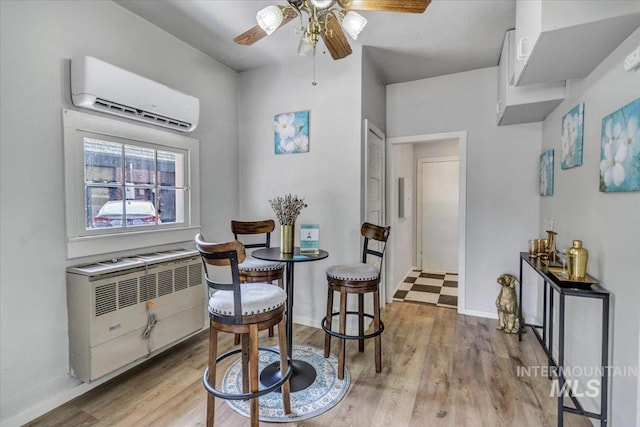 dining room featuring ceiling fan, radiator, a wall mounted AC, and light hardwood / wood-style floors