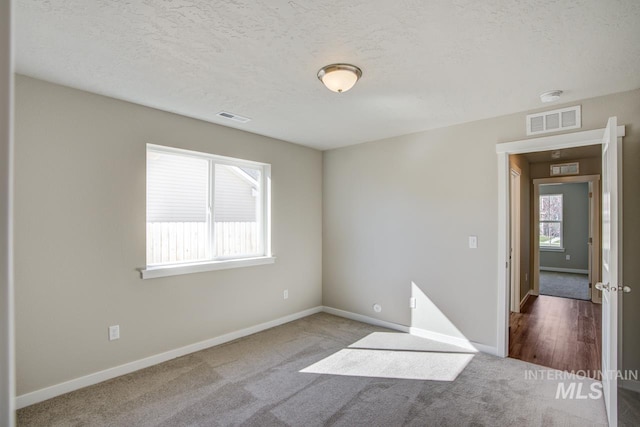 carpeted spare room with a textured ceiling