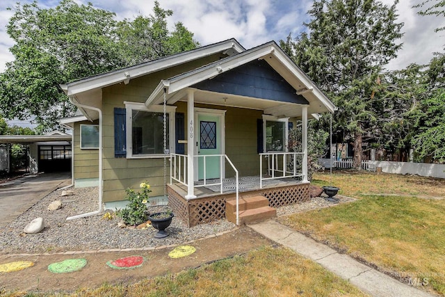 view of front of home featuring a front yard, an attached carport, and covered porch