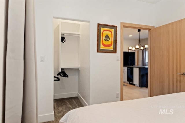 carpeted bedroom with a spacious closet, a closet, an inviting chandelier, and baseboards