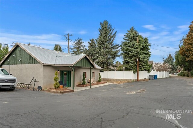 view of front of house with metal roof, stucco siding, and fence