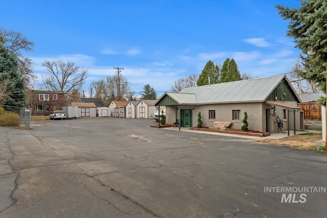 exterior space featuring a shed, stucco siding, an outdoor structure, fence, and metal roof
