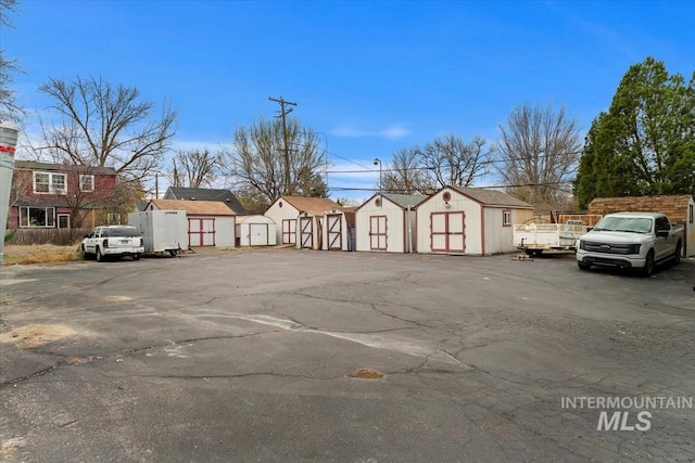 view of vehicle parking featuring a storage unit and a residential view