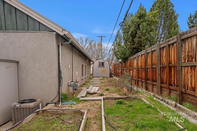 view of yard with an outbuilding, central air condition unit, a fenced backyard, a vegetable garden, and a storage shed