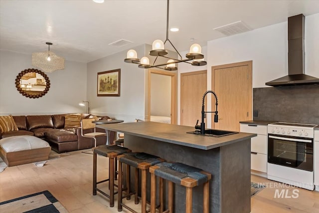 kitchen featuring a sink, white electric stove, dark countertops, wall chimney range hood, and visible vents