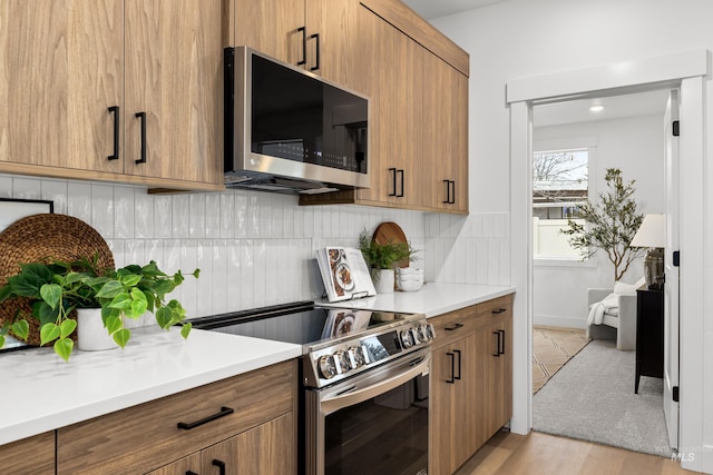 kitchen with stainless steel appliances, light hardwood / wood-style floors, and tasteful backsplash