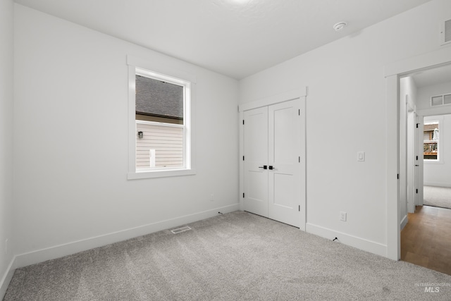 unfurnished bedroom with a closet, multiple windows, and carpet