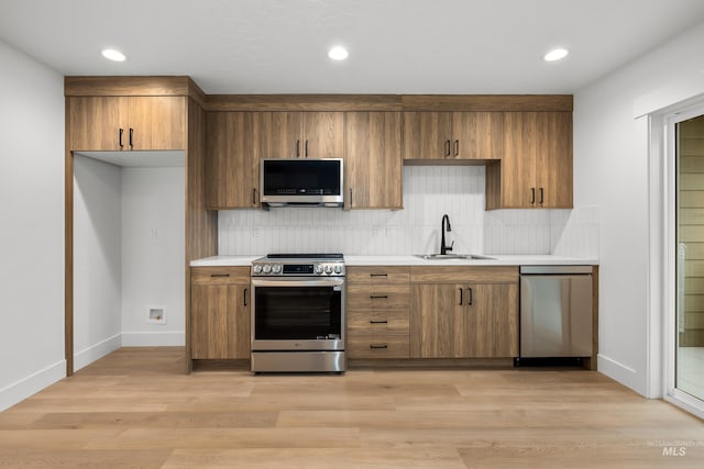 kitchen featuring stainless steel appliances, decorative backsplash, sink, and light hardwood / wood-style floors