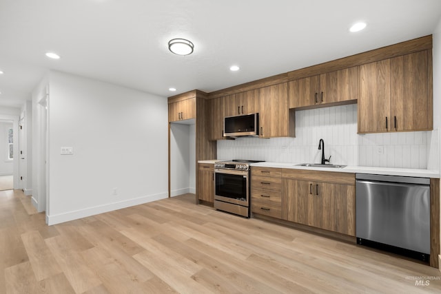 kitchen with sink, stainless steel appliances, light wood-type flooring, and decorative backsplash