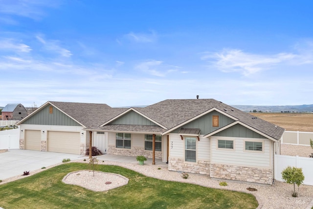 view of front of property with fence, a shingled roof, stone siding, and board and batten siding