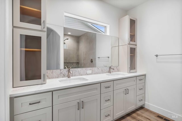 full bath with double vanity, visible vents, a tile shower, and a sink