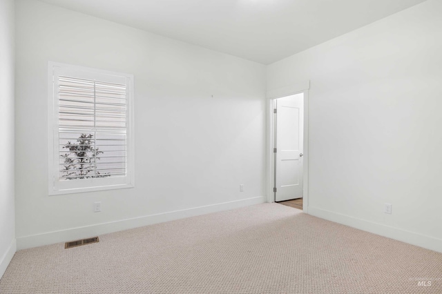 carpeted spare room featuring baseboards and visible vents