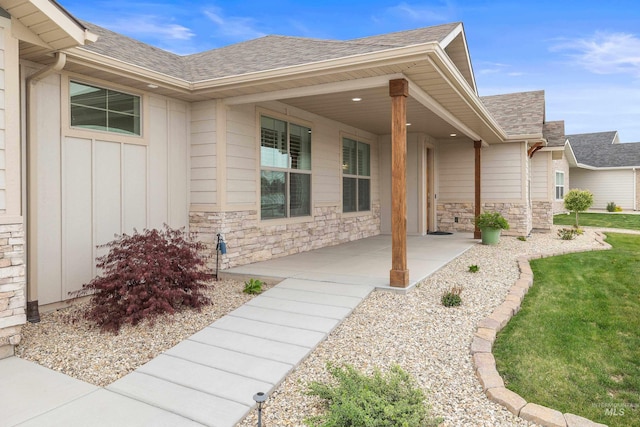 property entrance featuring a shingled roof, stone siding, and board and batten siding