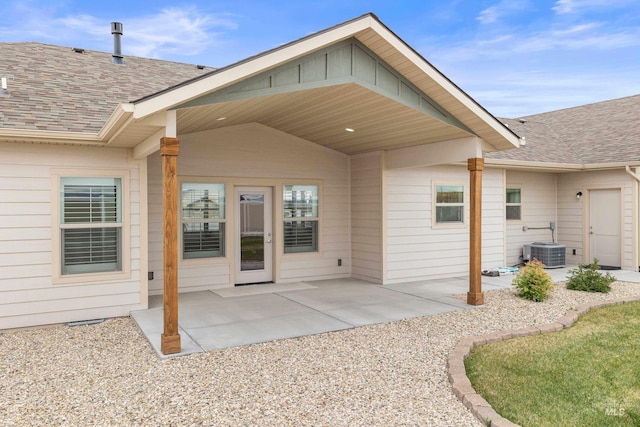 rear view of property featuring central AC unit, a patio area, a shingled roof, and board and batten siding