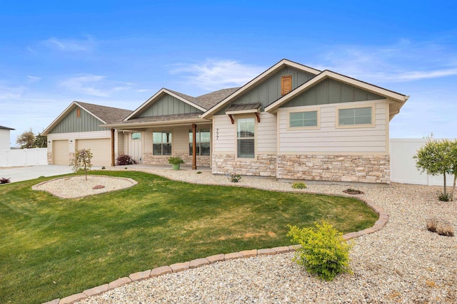 view of front of house with fence, stone siding, driveway, a front lawn, and board and batten siding
