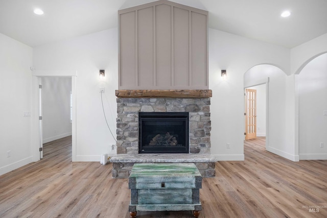 unfurnished living room with light wood-style flooring, recessed lighting, baseboards, arched walkways, and a fireplace