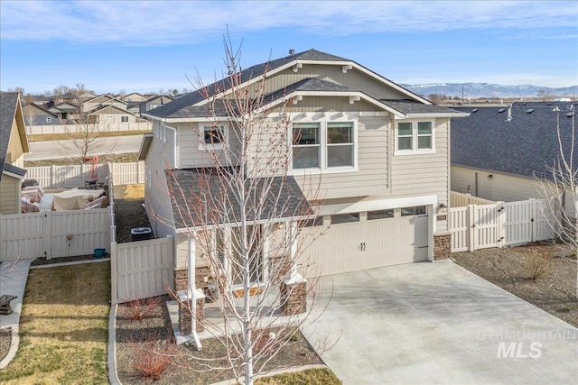 view of front facade with an attached garage, concrete driveway, fence, and a gate