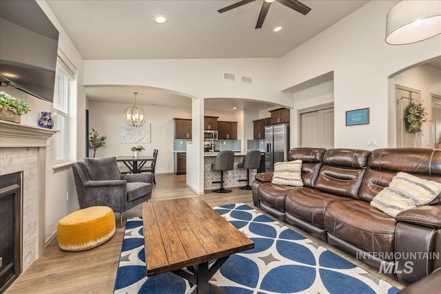 living area with visible vents, lofted ceiling, wood finished floors, and a fireplace