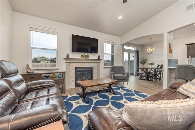 living room featuring visible vents, a notable chandelier, wood finished floors, and vaulted ceiling