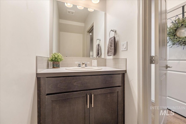 bathroom featuring vanity, visible vents, and backsplash