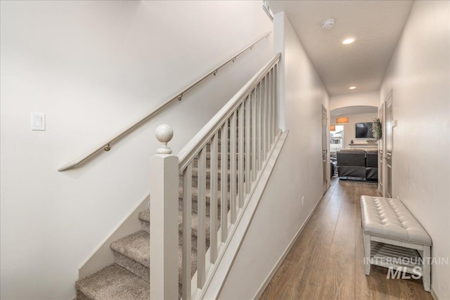 stairs featuring recessed lighting, wood finished floors, arched walkways, and baseboards