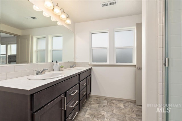 full bathroom featuring a sink, visible vents, double vanity, and stone finish flooring