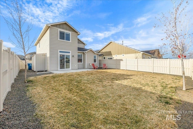 rear view of house featuring a patio area, a lawn, board and batten siding, and a fenced backyard