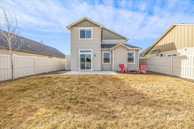 back of property with a fenced backyard, a yard, board and batten siding, and a patio