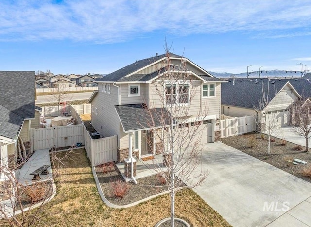 rear view of house with a gate, fence, roof with shingles, concrete driveway, and an attached garage