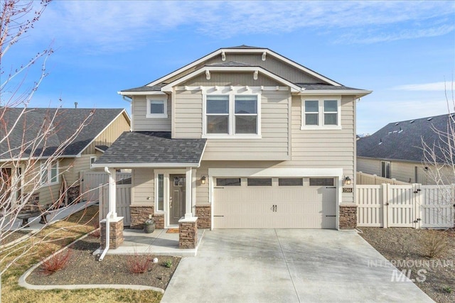 craftsman-style home featuring a gate, fence, driveway, a garage, and stone siding