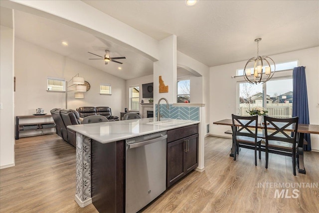 kitchen featuring light wood finished floors, dark brown cabinets, open floor plan, light countertops, and stainless steel dishwasher