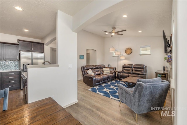 living area featuring ceiling fan, lofted ceiling, recessed lighting, arched walkways, and dark wood-style flooring