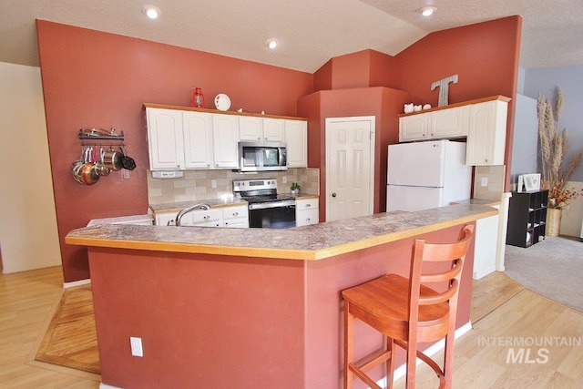 16696 Snowgoose St, Nampa, ID 83687 - kitchen with stainless steel appliances, a breakfast bar, light wood-style flooring, white cabinets, and lofted ceiling