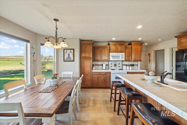 2020 Widner Rd, Midvale, ID 83645 - kitchen featuring white appliances, brown cabinetry, a chandelier, tasteful backsplash, and a kitchen breakfast bar