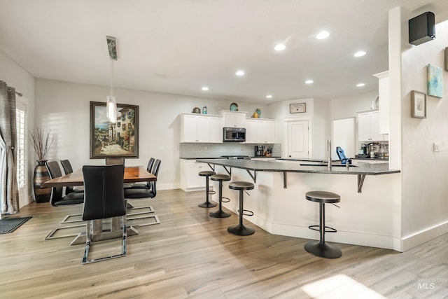 2679 S Tristram Way, Meridian, ID 83642 - kitchen featuring stainless steel microwave, a kitchen breakfast bar, recessed lighting, light wood-style flooring, and decorative backsplash