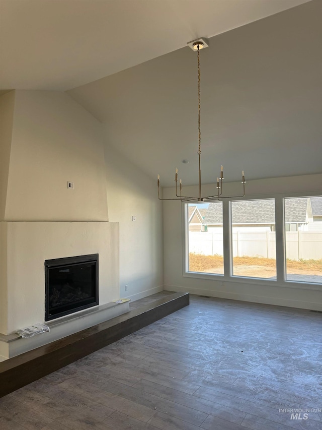 unfurnished living room featuring vaulted ceiling, hardwood / wood-style flooring, and a notable chandelier