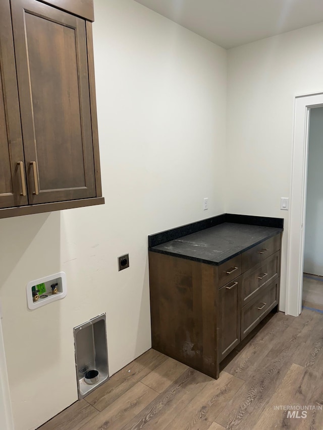 clothes washing area with hookup for an electric dryer, light hardwood / wood-style floors, washer hookup, and cabinets