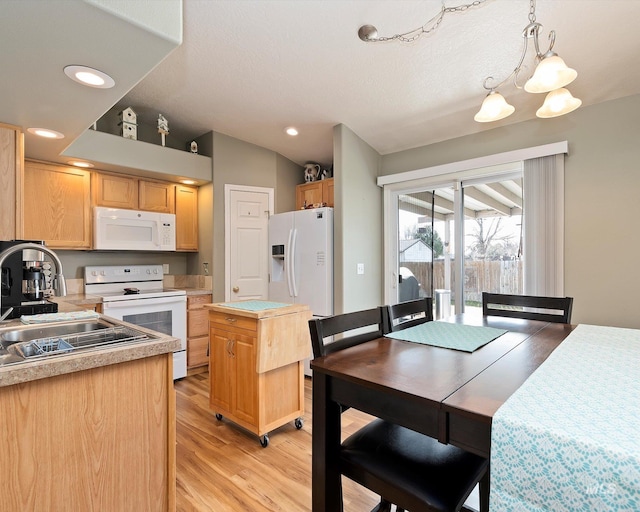 kitchen featuring white appliances, light countertops, light brown cabinets, and a sink