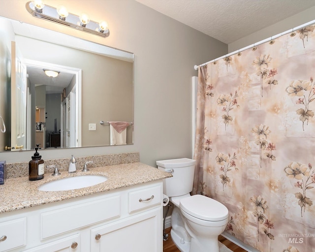 full bath with vanity, toilet, and a textured ceiling