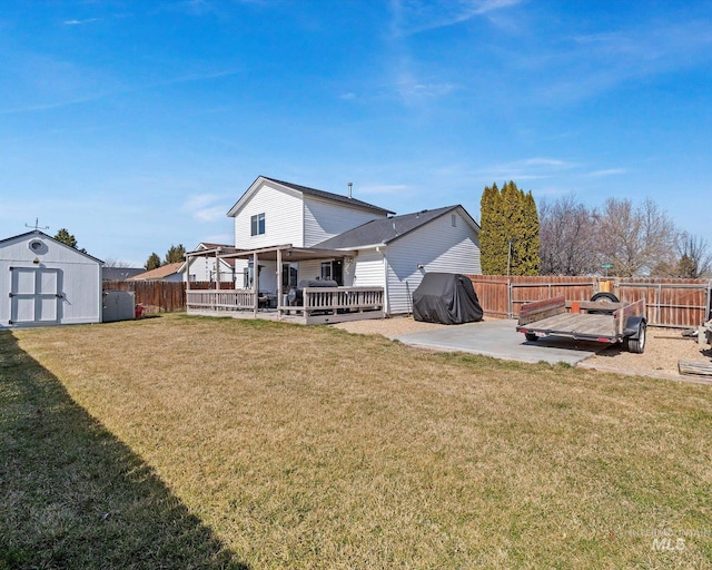 rear view of property featuring a storage shed, a fenced backyard, a yard, an outbuilding, and a patio