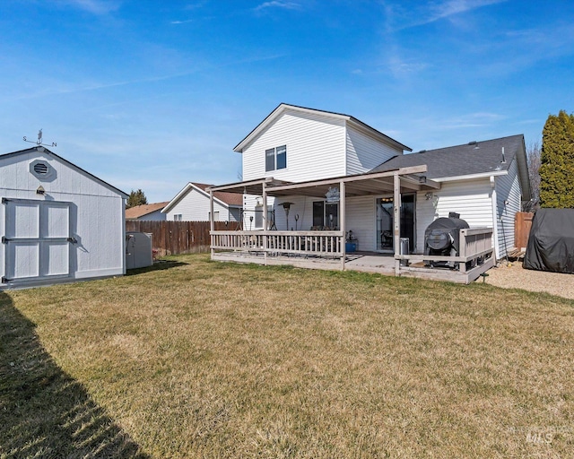 back of house featuring a storage shed, an outbuilding, a yard, and fence