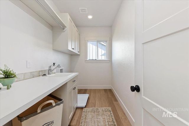 laundry area with sink, light hardwood / wood-style flooring, cabinets, and washer hookup