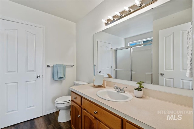 bathroom with toilet, vanity, a shower with shower door, and hardwood / wood-style floors