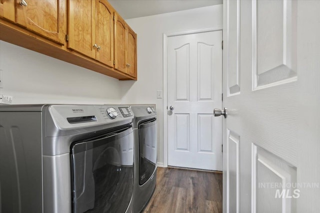 washroom with washing machine and dryer, cabinets, and dark wood-type flooring