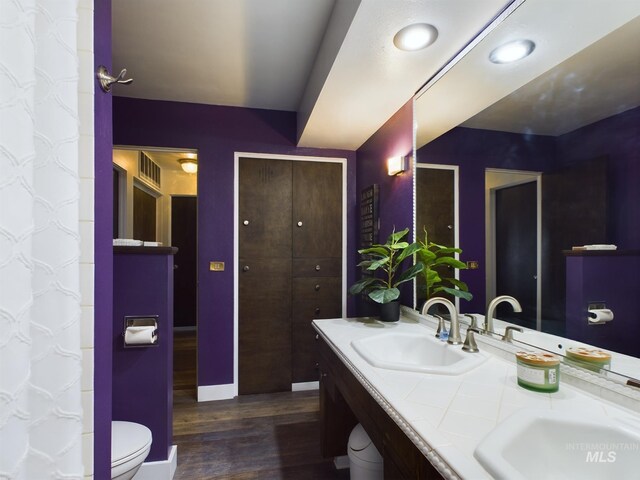 bathroom featuring dual vanity, wood-type flooring, and toilet