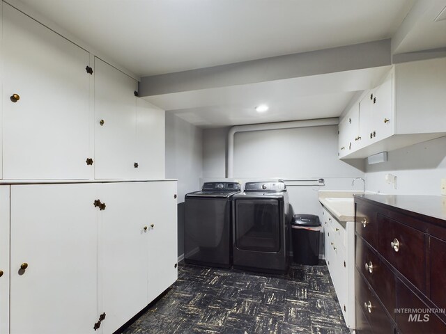 kitchen with white cabinets, sink, dark tile patterned flooring, and washer and clothes dryer