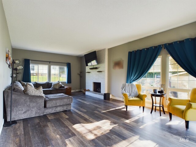 living room with brick wall, a fireplace, plenty of natural light, and wood-type flooring