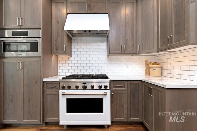 1512 E Rivers End Ct, Eagle, ID 83616 - kitchen with white gas range oven, premium range hood, stainless steel oven, and tasteful backsplash