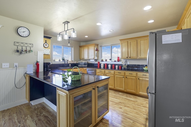 kitchen with a healthy amount of sunlight, stainless steel appliances, decorative light fixtures, and light hardwood / wood-style flooring